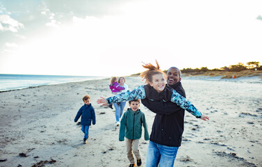 Father and daughter having fun on the beach with family