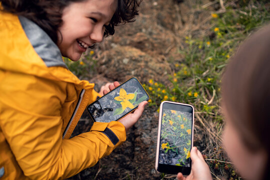Children exploring nature and taking photos with smartphones