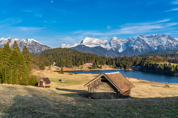 Geroldsee und mehrere alte Holzhütte mit schneebedecktem Alpenpanorama bei Garmisch-Patenkirchen