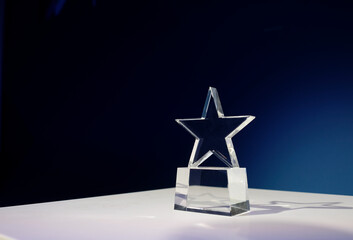 Star-shaped award made of glass on a white table with a spotlight on it and copy space