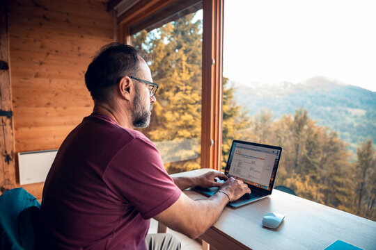 Man working on laptop in home with mountain view