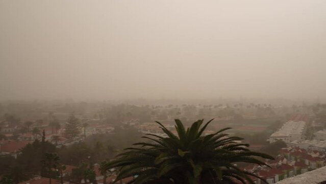 The hot wind from Calima causes a sandstorm and blocks the view from Playa del Ingles over Maspalomas. Climate change concept