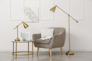 Interior of light living room with armchair, table and lamps