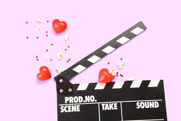 Movie clapper with popcorn, confetti and hearts on lilac background. Valentine's Day celebration