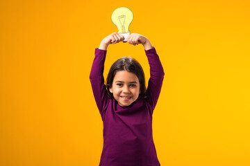 Thoughtful child girl holding paper bulb above head. Success, motivation, winner, genius, idea...