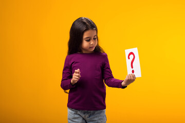 Thoughtful kid girl holding question mark card. Children, idea and knowledge concept