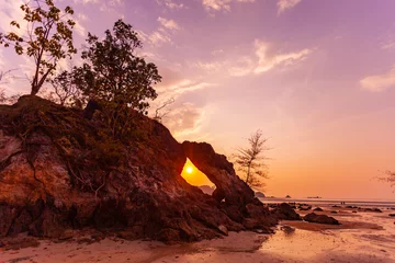 Poster amazing The evening sun shone through the large rock hole and sparkled beautifully. .stunning sunset in the hole of unusual rock wave eroded into .the cavity like the arch with a hole.. © Narong Niemhom