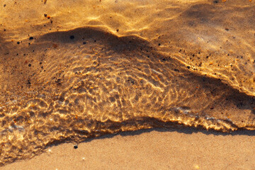 The sandy bottom of the lake, waves and ripples in shallow water