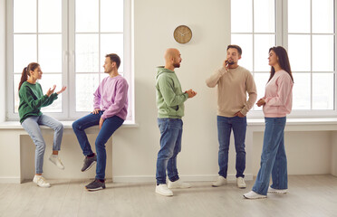 Group of business people or students in casual clothes men and women chatting on a meeting. Company employees or friends team talking and communicating with each other gathering indoors.