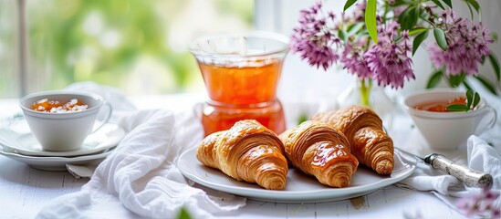 A white plate is filled with freshly baked croissants, accompanied by a cup of tea, serving as a delightful Continental breakfast.