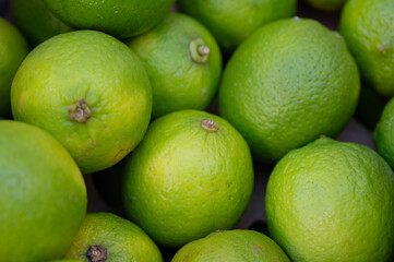 Limes close-up on a street stall tray. Fresh fruits and vegetables. Background with juicy and bright products.
