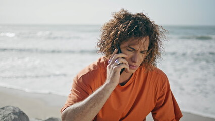 Upset traveler talking phone sitting on beautiful sunny beach alone close up.