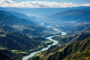 Naklejka premium A river meanders through a valley, flanked by towering mountains on either side