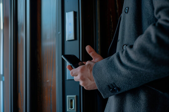 Hand man closely with the phone, the businessman uses the application on the smartphone to remove the door opening of the house, office