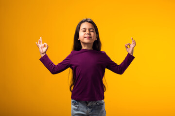 Kid girl smiling peacefully holding his fingers in mudra gesture, meditating. Zen, meditation,...