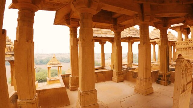 4K moving shot of pillars of the cenotaphs and Royal Chhatris in Thar desert at Jaisalmer, Rajasthan, India. View of desert from inside cenotaphs of Bada Bagh. Historical Indian architecture.