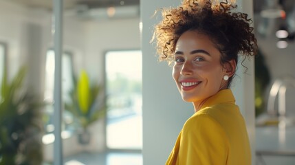 Smiling woman in a yellow blouse in a bright office, radiant and approachable - obrazy, fototapety, plakaty