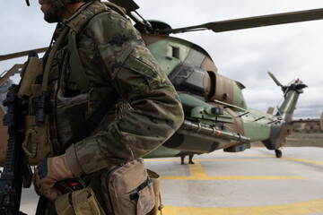 Un militar armado al lado de un helicóptero de ataque Tigre.