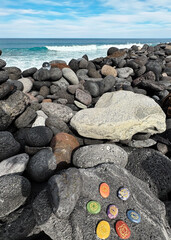 Healing crystals, chakra stones. Rainbow gemstones in a circle on grey volcanic ocean shore.