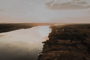 a small village with small houses near a wide, clean, calm river