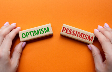 Optimism or Pessimism symbol. Concept word Optimism or Pessimism on wooden blocks. Businessman hand. Beautiful orange background. Business and Optimism or Pessimism concept. Copy space