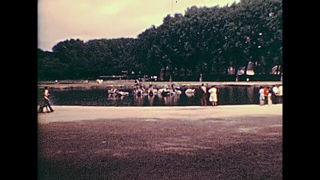PARIS, FRANCE - CIRCA 1976: Tourists looking the Quadriga statue in the Apollo fountain at Palace of Versailles garden. Historic archival footage in Paris city of France in 1970s.