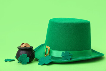 Pot with golden coins, leprechaun hat and clovers on green background. St. Patrick's Day celebration