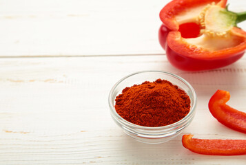 Paprika powder in plate with fresh red pepper on white background.