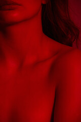 Female body in red lighting. Women's shoulders and collarbones