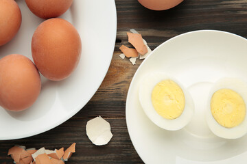 Boiled eggs on plate on brown wooden background.