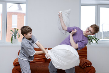 Pillow fight day. Two teenage brothers are fighting with pillows