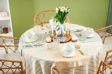 Table setting with tulip flowers for International Women's Day celebration in stylish room near green wall