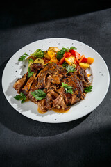 Close-up of beef brisket with roasted vegetables on a white plate
