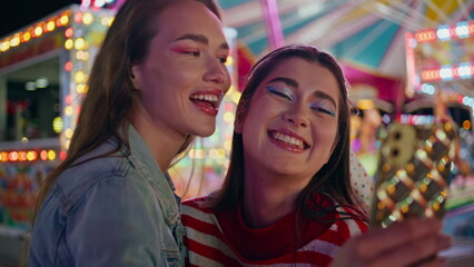 Funny friends taking mobile phone selfie closeup. Joyful girls resting funfair