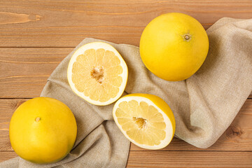 Tasty whole and cut pomelo fruits with napkin on wooden background