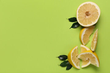 Tasty cut pomelo fruit with slices and leaves on green background