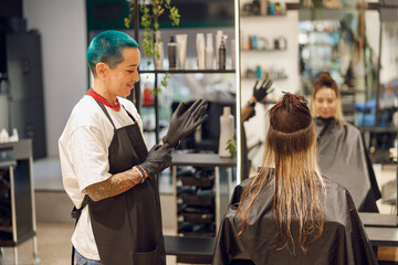 Professional colorist putting on gloves before coloring hair in beauty salon - obrazy, fototapety, plakaty
