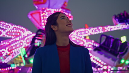 Happy girl enjoying amusement park at night. Cheerful beautiful model at neon