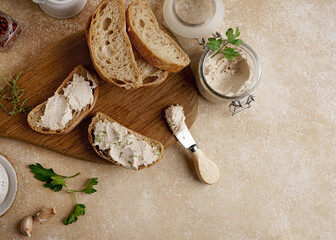 Homemade pate, spread or mousse in glass jar with sliced bread and herbs with pine nuts, light concrete background.