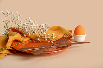 Beautiful festive table setting for Easter with egg on beige background