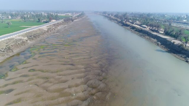A canal of the Indus River whose water has dried up in winter. A beautiful drone shot of the sand bank in the canal. Aerial drone view over the river during the day. 4K footage.