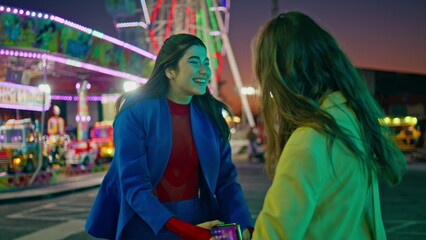 Obraz premium Happy best friends embracing meeting at amusement park. Smiling girls resting