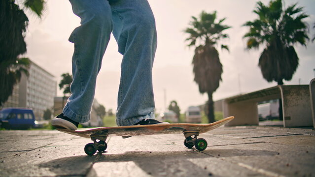 Feet skateboarder performing trick with longboard at summer sunlight outdoors.