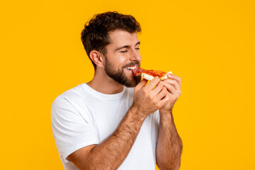 Portrait of young guy holds and savors tasty pizza slice