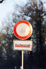 Water flood sign Hochwasser - Flood at Germany forest city park. Road close drive prohibited due...