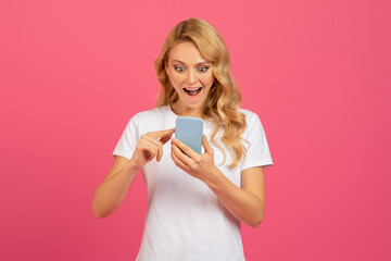 Excited blonde lady with smartphone scrolling applications over pink background