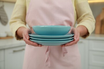 Woman holding plates in kitchen, closeup view