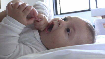 Cute baby infant putting foot in mouth and getting up feeling happy and joy