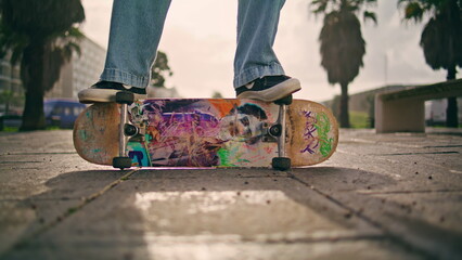 Closeup feet skateboarder standing on side skate at street. Guy practicing hobby