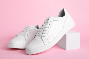 Pair of stylish white sneakers on pink background